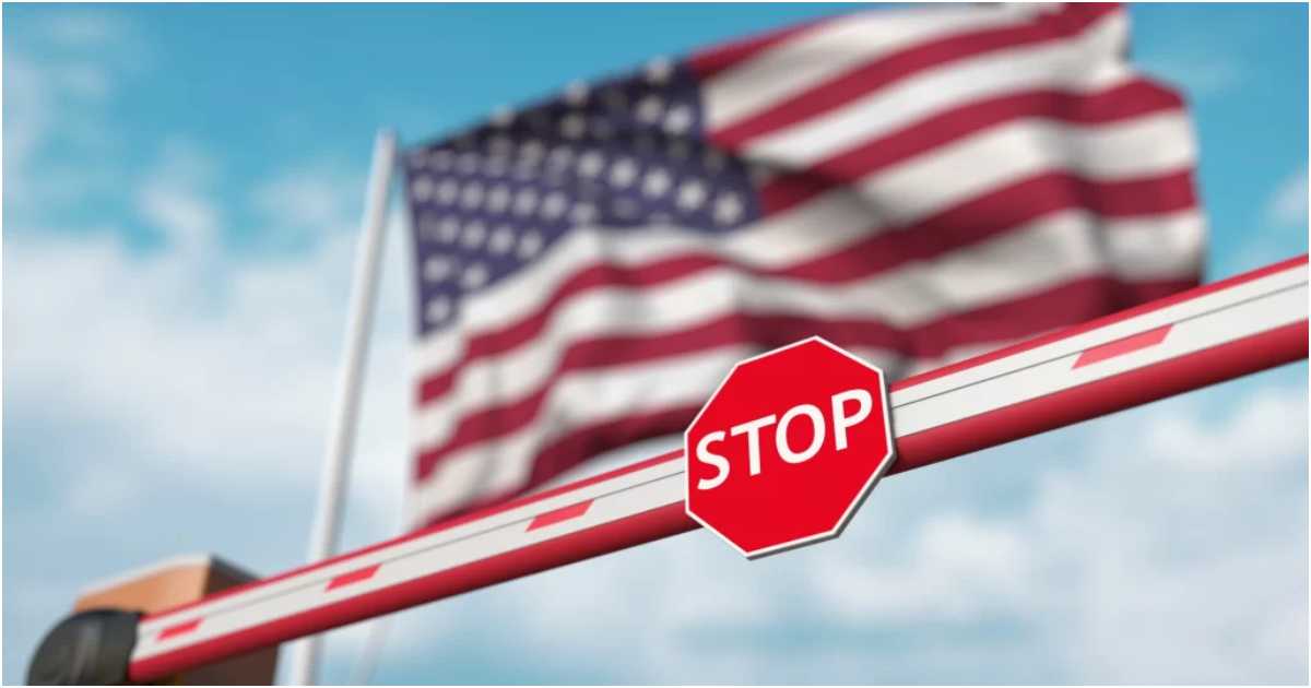 অ্যামেরিকার পতাকার পাশে একটি বারের ওপর ‘স্টপ’ লেখা। ছবি: মেনদোজা ফার্ম